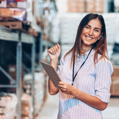 Smiling woman holding a digital tablet in a warehouse