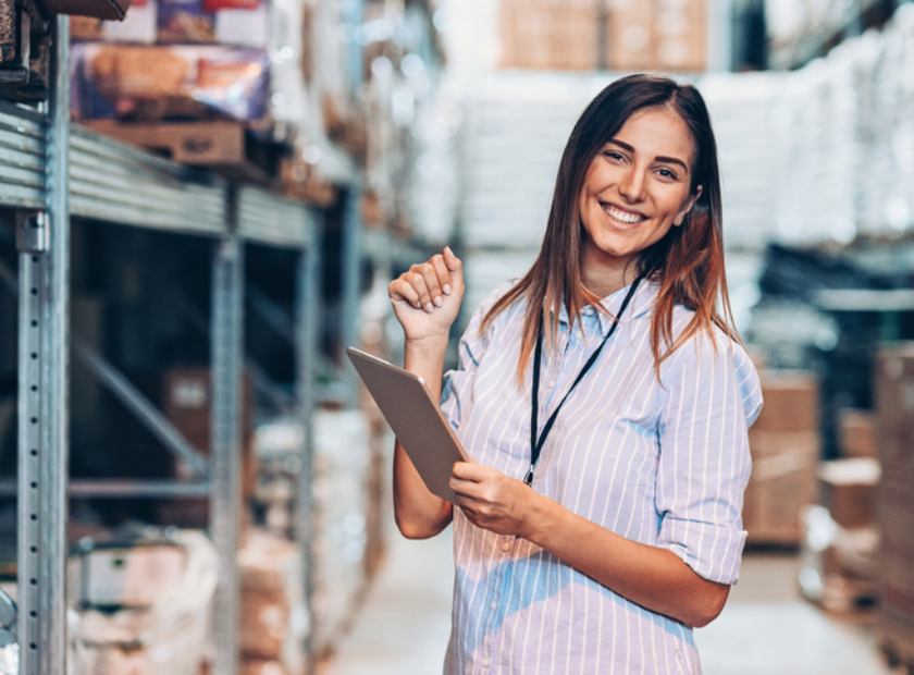 Smiling woman holding a digital tablet in a warehouse