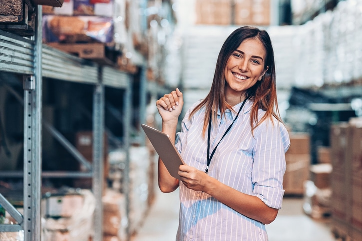 Smiling woman holding a digital tablet in a warehouse