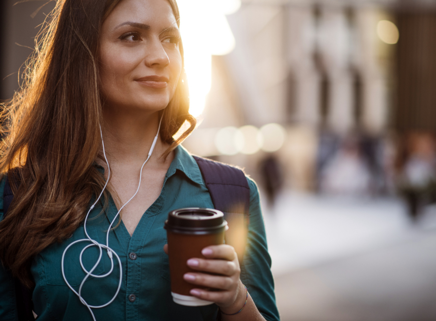Moderni nainen kuuntelee musiikkia, joka kantaa kahvimukia