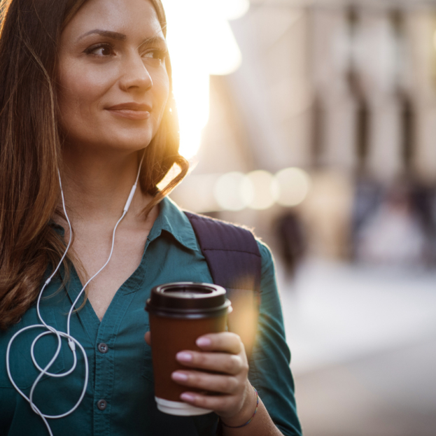 Modern woman listening to music carrying coffee mug