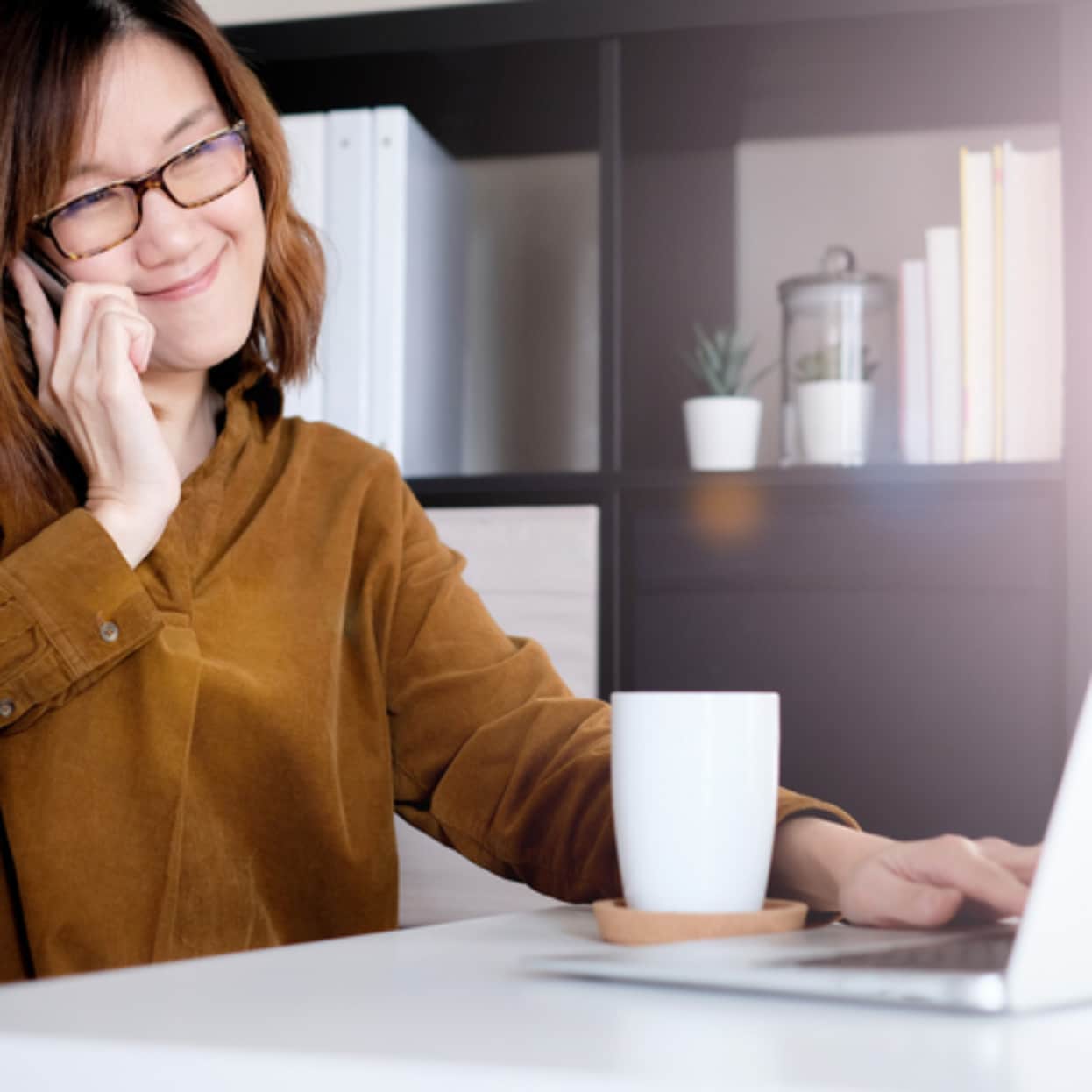 Woman using a phone and lap top