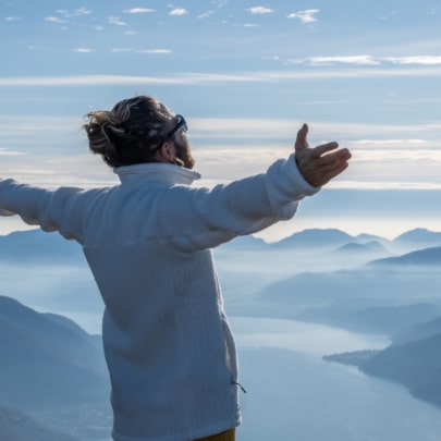 Hiker stands arms out on mountain top