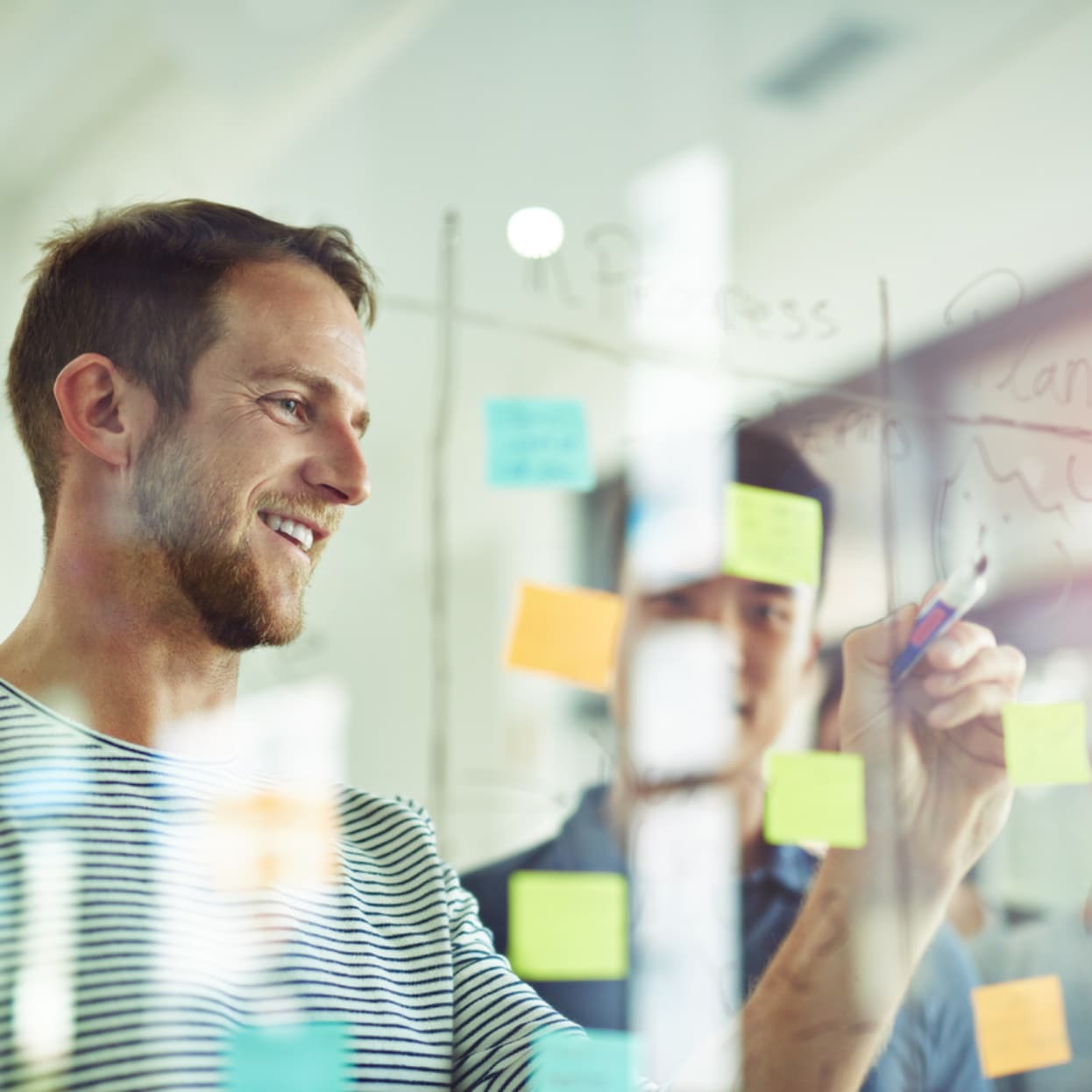 ERP project manager using sticky notes on a glass wall during a meeting