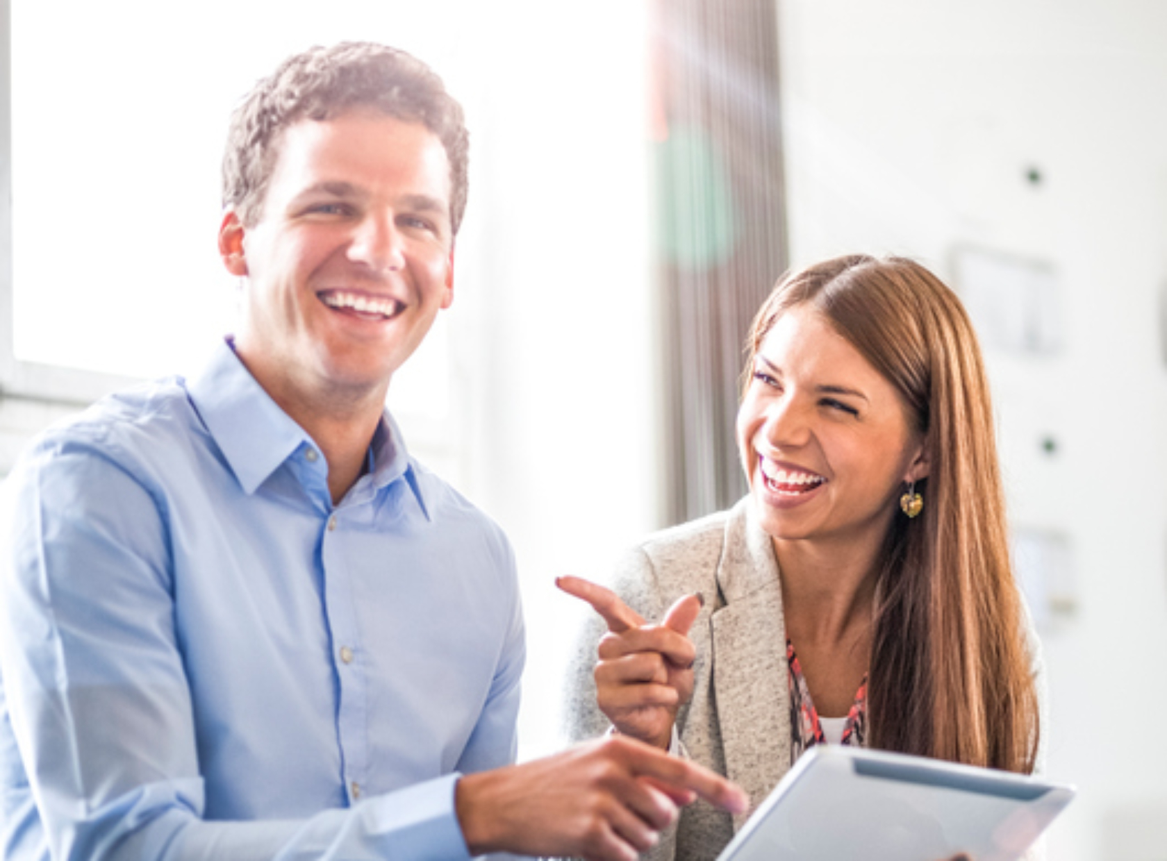 Portrait of cheerful businessman with female colleague using digital tablet in office
