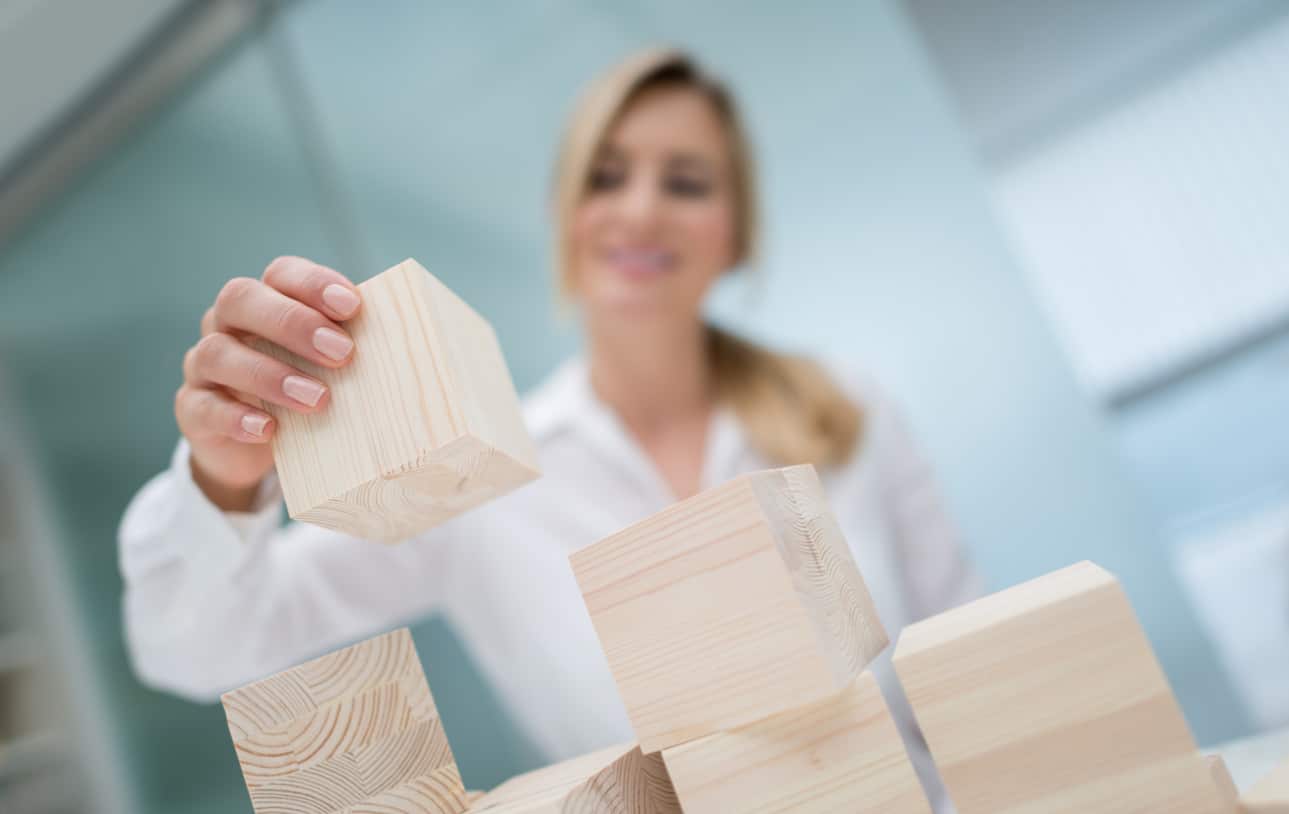 woman with wooden blocks building a tower