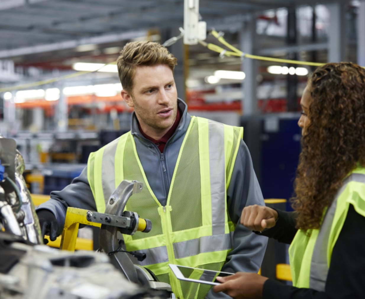 Multi-ethnic engineers discussing over car chassis