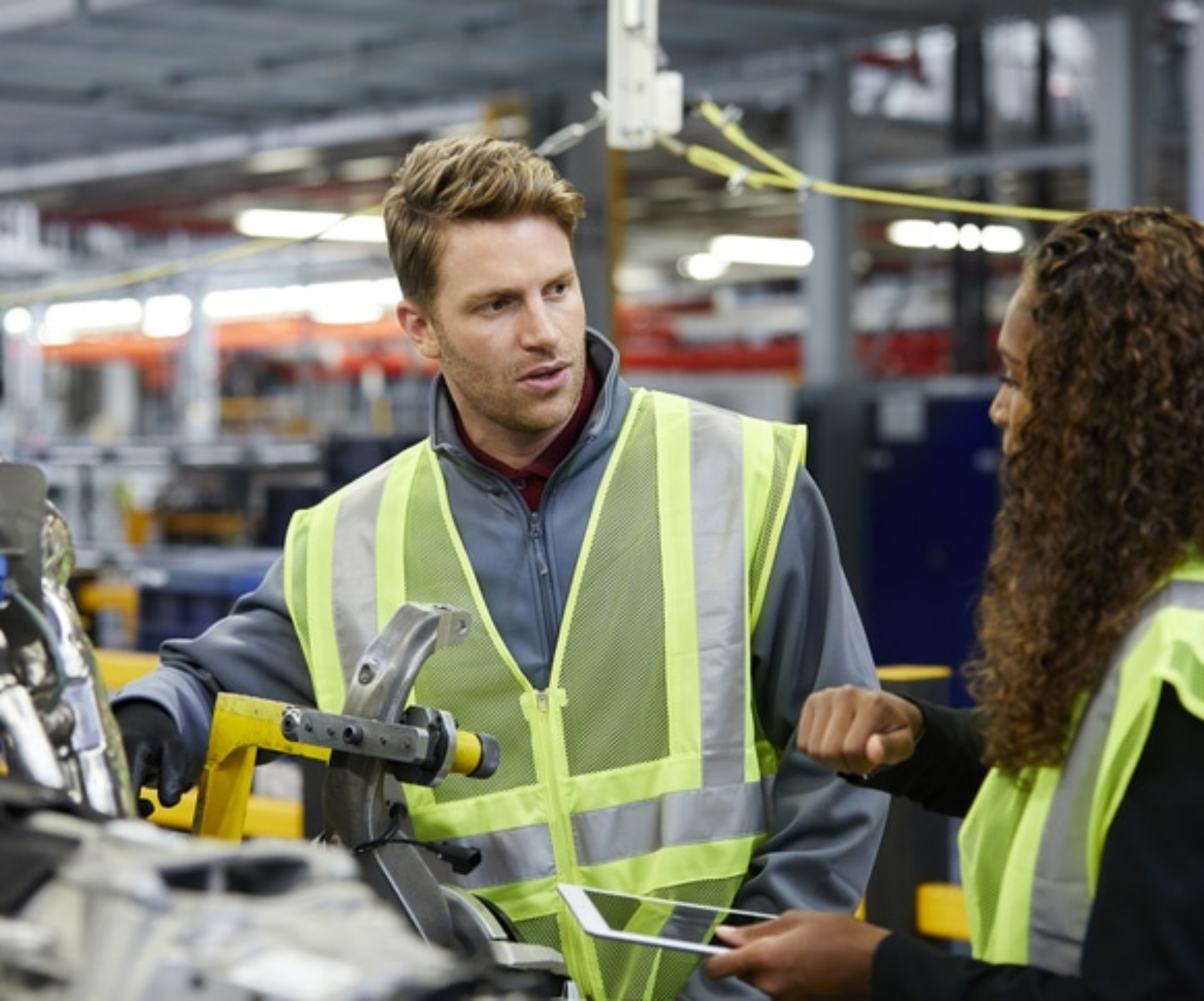 Multi-ethnic engineers discussing over car chassis